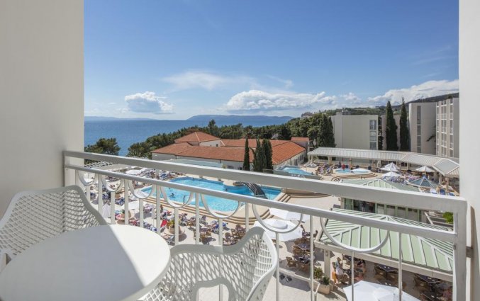 Balkon met uitzicht op het zwembad en de zee van Hotel Bluesun Alga in Dalmatië